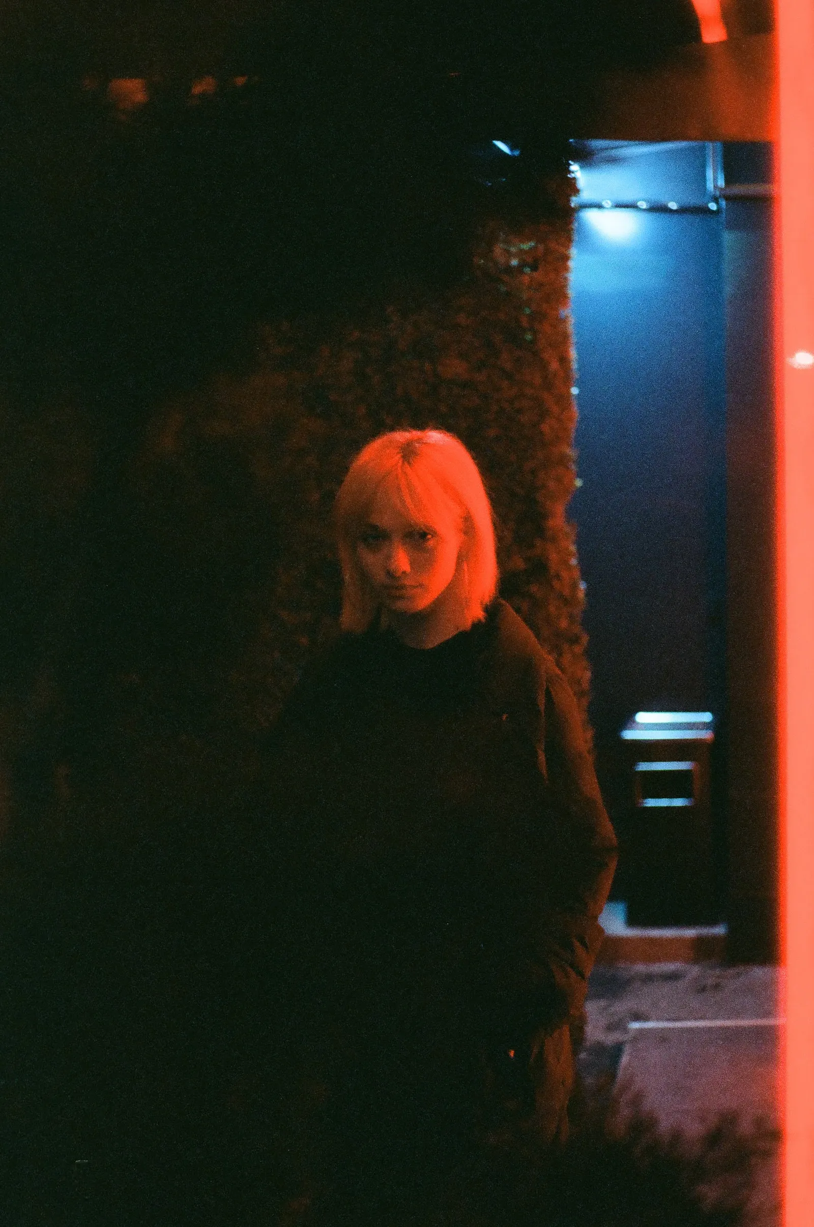Oana almost swallowed by the dark, a single band of red light across the frame